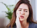 Kobieta z bólem zęba po zatruciu, szuka pomocy.