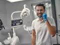 Uśmiechnięty dentysta w gabinecie. Zastanawiasz się, ile trwa plombowanie zęba? Krótka wizyta i piękny uśmiech!