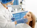 Dentystka bada uśmiechniętą pacjentkę, która nie odczuwa bólu okostnej.