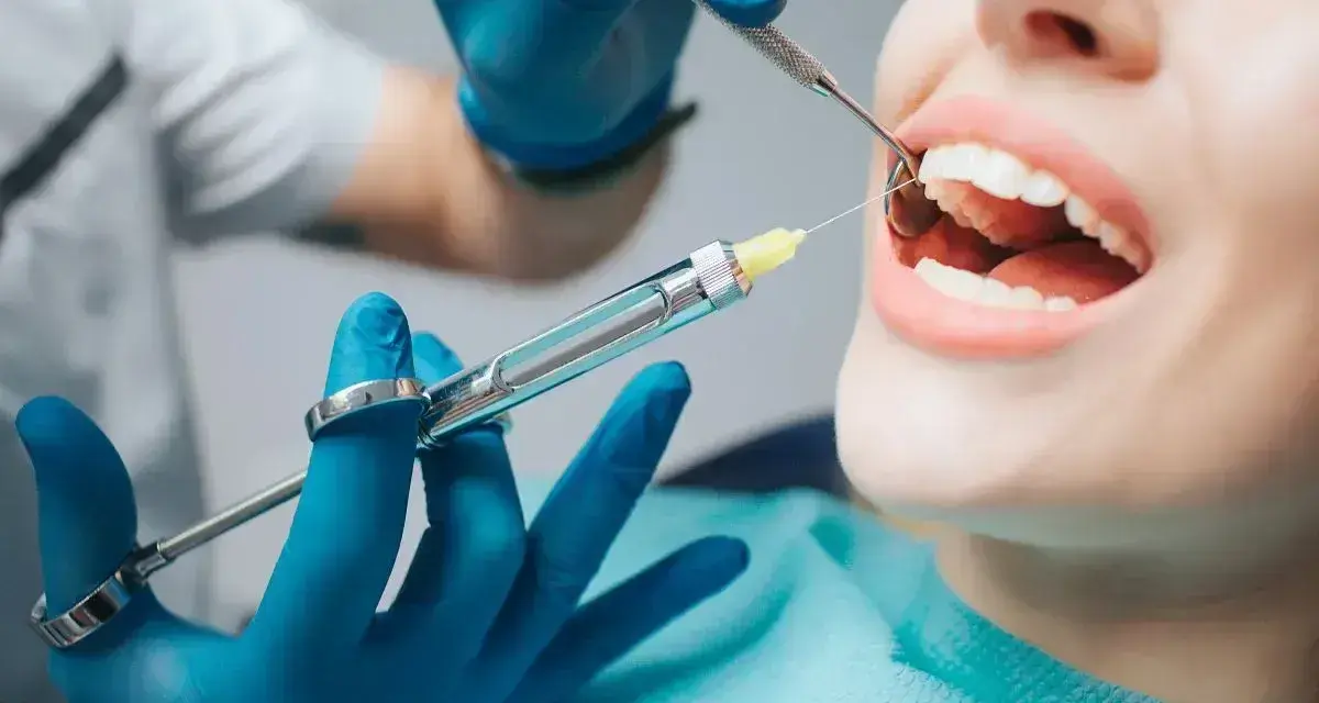 Dentysta podaje znieczulenie. Zamiast domowych sposobów na ruszające się zęby, warto zaufać profesjonalistom.
