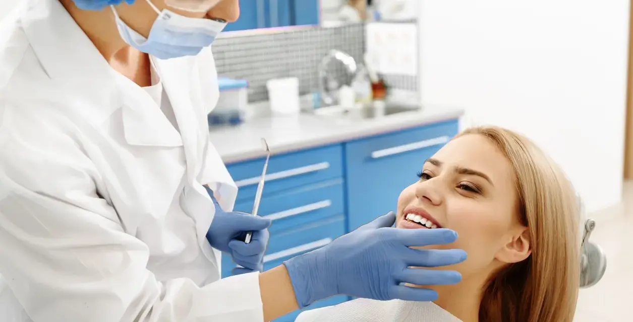 Dentystka bada uśmiechniętą pacjentkę, która nie odczuwa bólu okostnej.