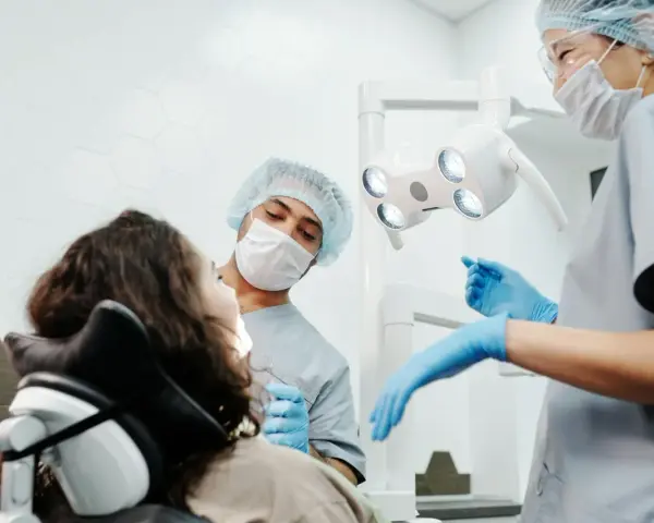 Dentysta przeprowadza leczenie zachowawcze zęba u pacjentki. Asystentka przygotowuje narzędzia.