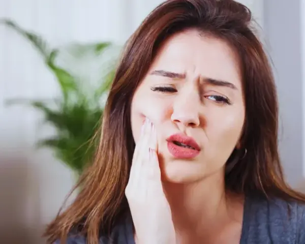 Kobieta z bólem zęba po zatruciu, szuka pomocy.