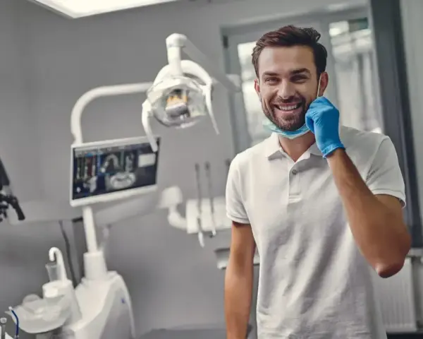 Uśmiechnięty dentysta w gabinecie. Zastanawiasz się, ile trwa plombowanie zęba? Krótka wizyta i piękny uśmiech!