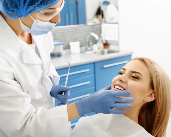 Dentystka bada uśmiechniętą pacjentkę, która nie odczuwa bólu okostnej.