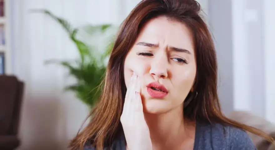 Kobieta z bólem zęba po zatruciu, szuka pomocy.