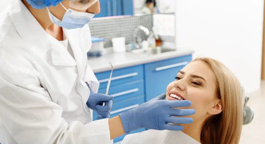 Dentystka bada uśmiechniętą pacjentkę, która nie odczuwa bólu okostnej.